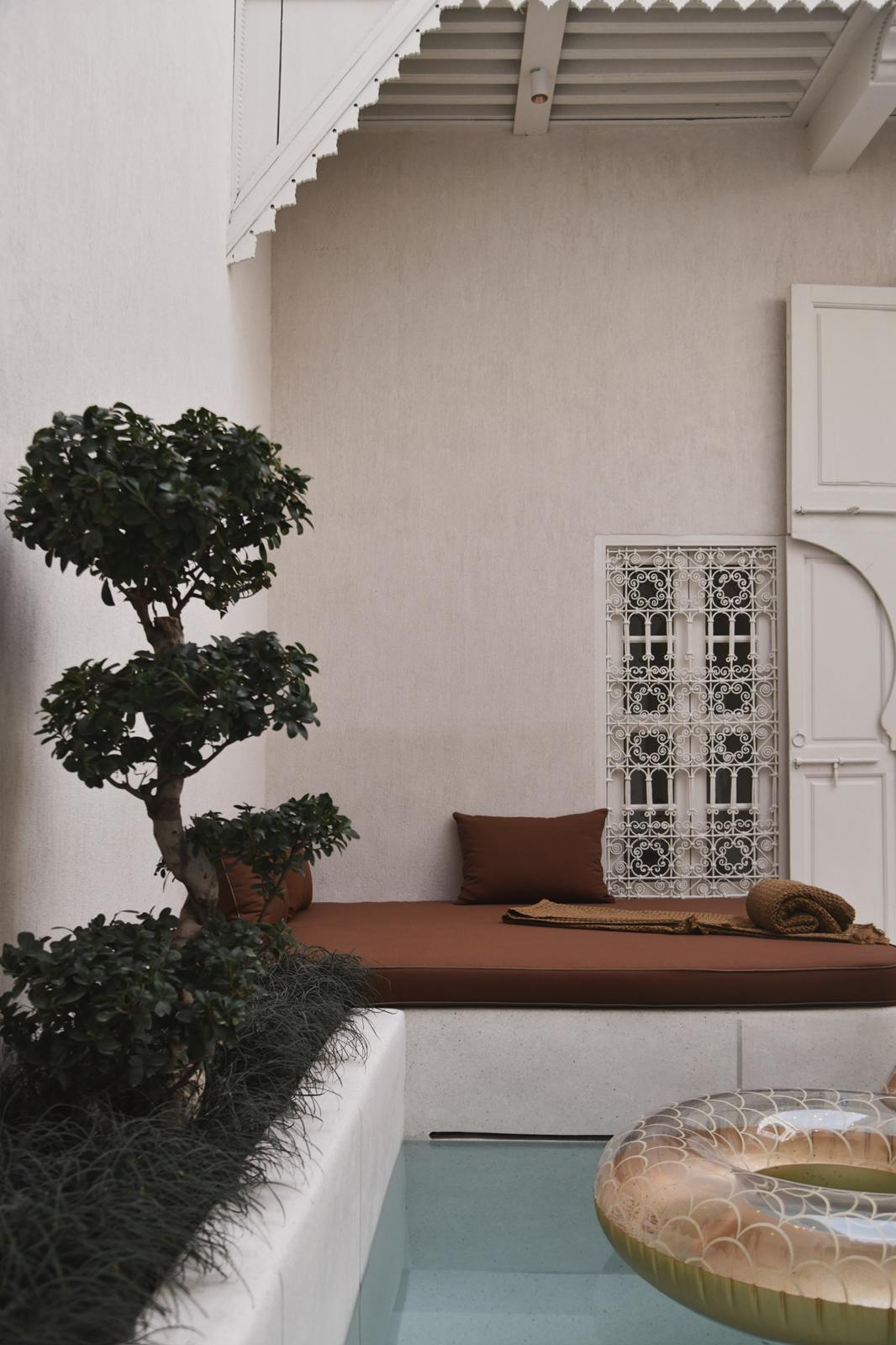 Riad Japandi poolside banquette with terracotta cushions beneath a scalloped white pergola