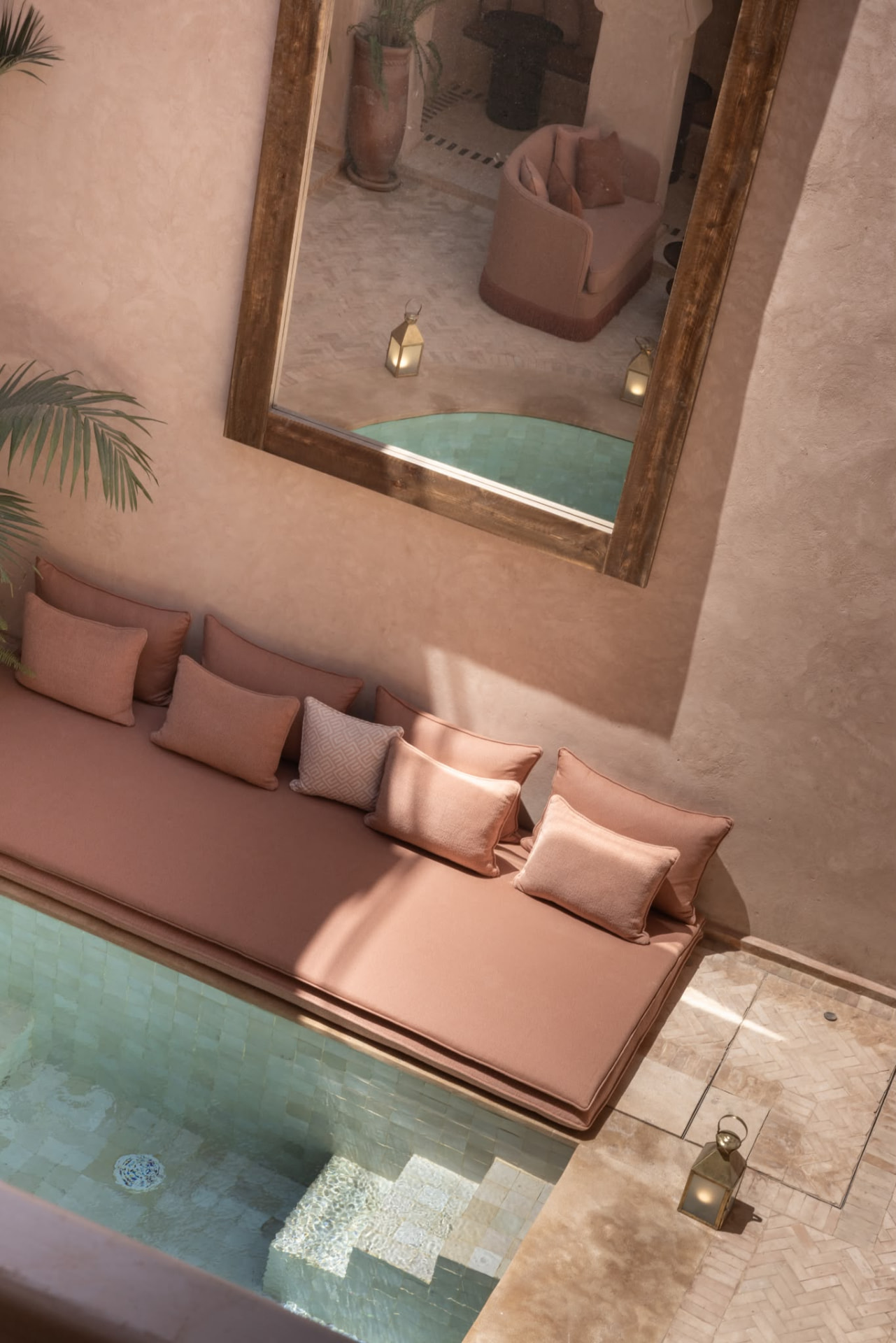 Lounge bench with blush cushions and a large antique mirror reflecting the Riad Beij pool