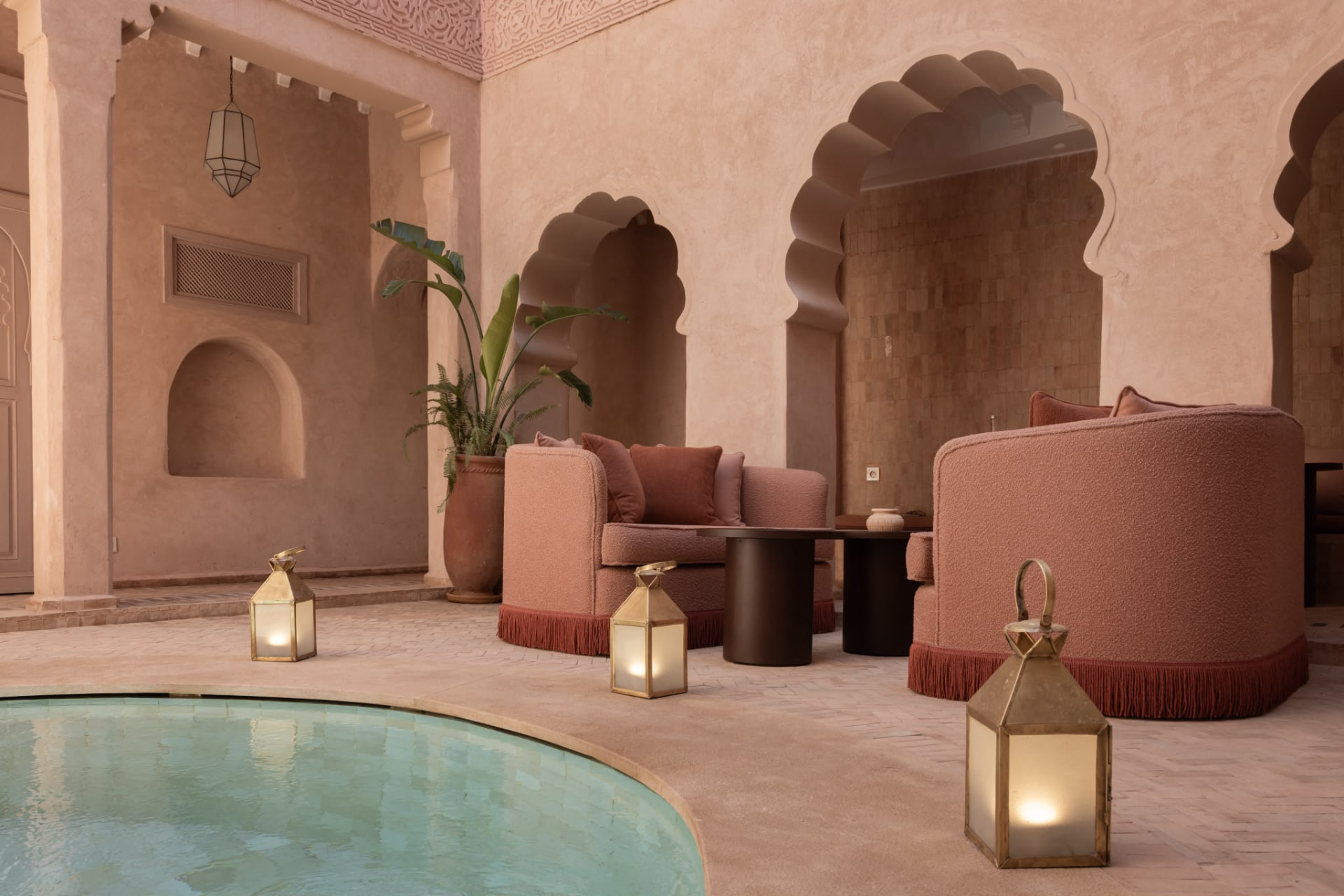 Courtyard of Riad Beij with scalloped arches and blush armchairs by the pool