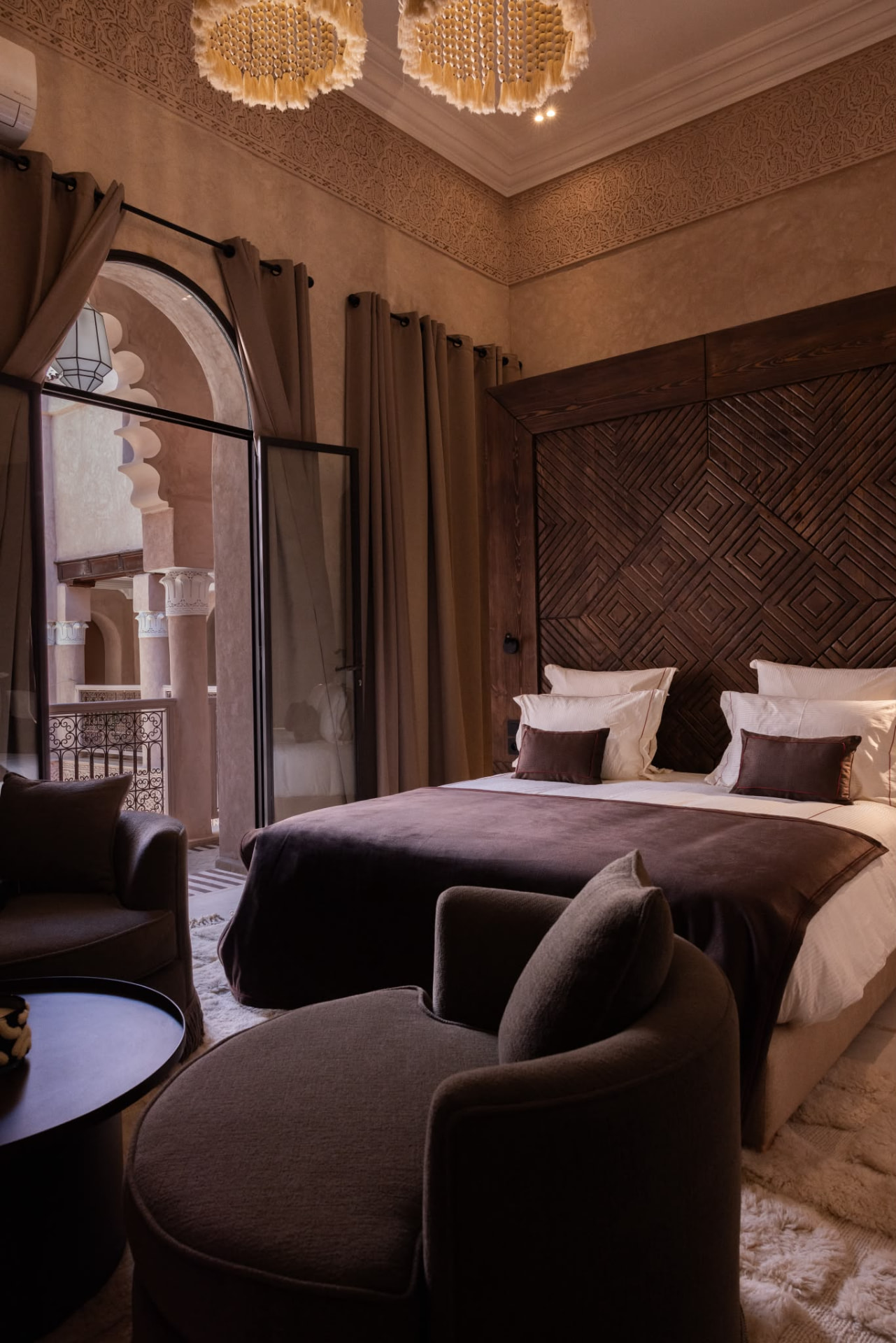 Riad Beij suite with sculpted plaster frieze, tassel chandeliers and dark timber joinery