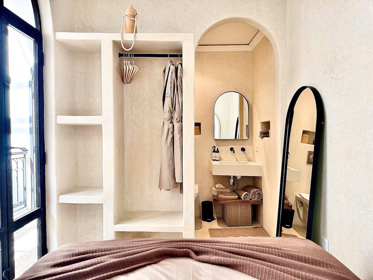 Riad Ambre dressing room and bathroom carved into soft plaster alcoves behind an arched opening
