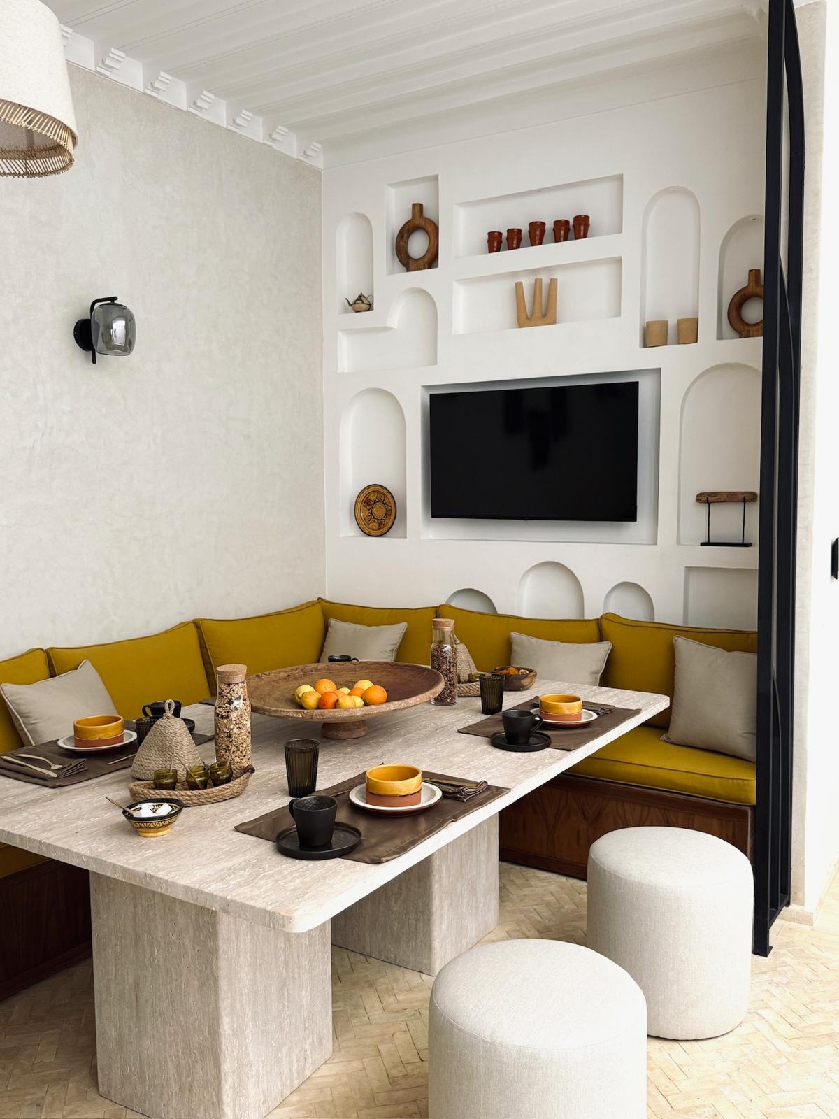 Riad Ambre dining table set with ceramics, oranges and tea glasses before sculpted wall niches