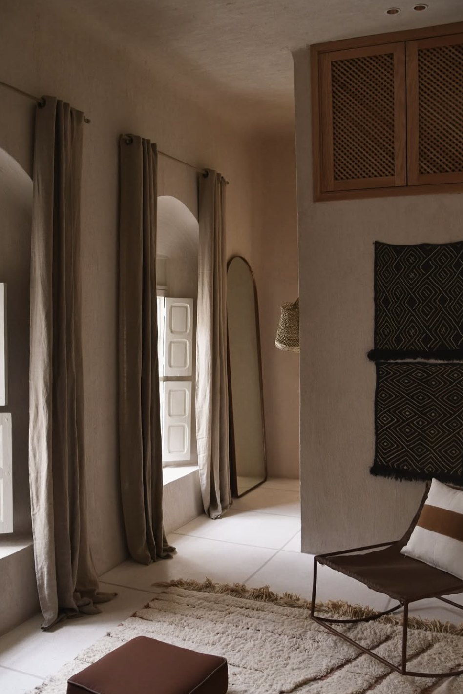 Riad Japandi corner with linen curtains, an arched mirror and a woven pendant light