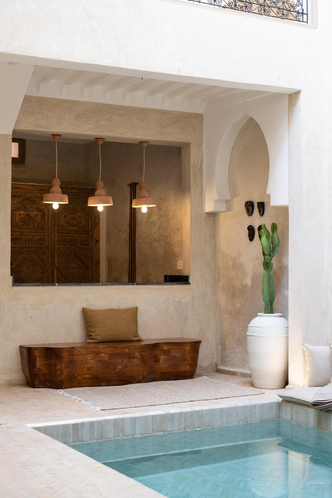 Kasbah Lover poolside corner with a carved wooden bench, terracotta pendant lights and a tall cactus